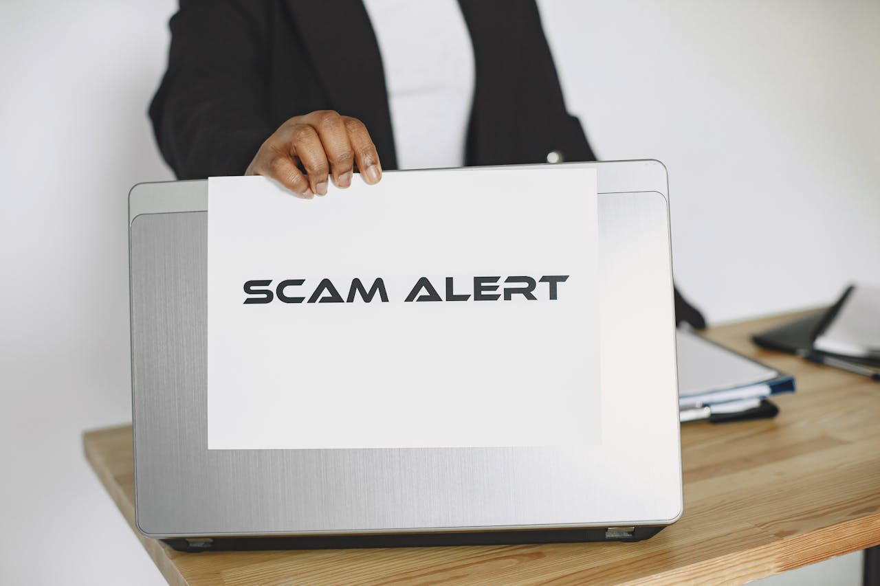 testimonials-img Business person holding a scam alert sign over a laptop, warning against online fraud.